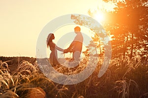 Young couple holding hands. In nature sunrise