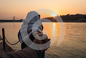 Young couple holding hands at sunset at ganges river bank from different angle