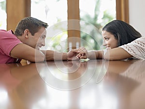 Young Couple Holding Hands On Table