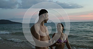 Young Couple Holding Hands Walking On Beach In Twilight Talking Tourists Man And Woman Together On Seaside