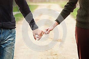 Young couple holding hands walking on a rural road at a summer sunset