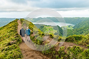 A young couple holding hands while walking towards the Grota do Inferno viewpoint at Sete Cidades on Sao Miguel Island, Azores