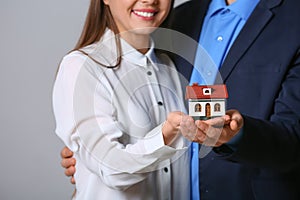 Young couple holding house model on grey background