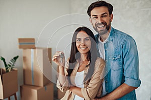 Young couple holding keys to a new house and feeling happy