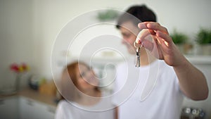 Young Couple Holding New House Keys. Close up shot of young couple hands holding key from their new stylish home on the