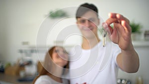 Young Couple Holding New House Keys. Close up shot of young couple hands holding key from their new stylish home on the