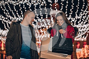 Young couple holding presents in a bags and having fun at night