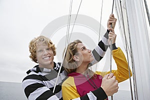 Young Couple Holding Rigging On Sailboat