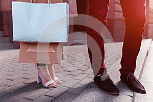 Young couple holding shopping bags after shopping on city street in summer. Closeup of purchases. Sale