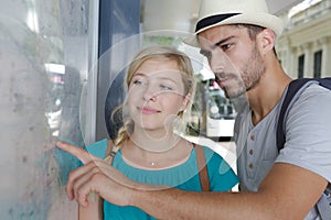 young couple on holiday looking at city map on wall