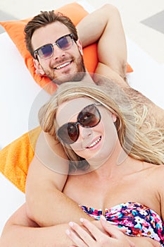 Young Couple On Holiday Relaxing By Swimming Pool