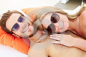 Young Couple On Holiday Relaxing By Swimming Pool