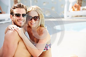 Young Couple On Holiday Relaxing By Swimming Pool