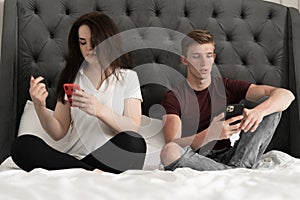Young couple at home in bed using mobile phones in relationship communication problem and internet social media network