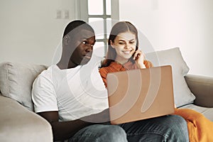 young couple at home on the couch in front of laptop watching movies