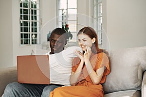 young couple at home in front of laptop watching movies vacation