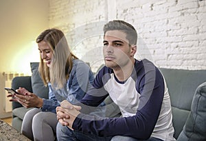 Young couple at home sofa couch with woman internet and mobile phone addiction ignoring her boyfriend feeling sad jealous frustrat