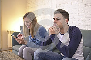 Young couple at home sofa couch with woman internet and mobile phone addiction ignoring her boyfriend feeling sad jealous frustrat