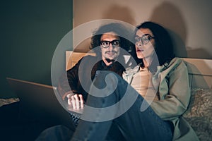 Young couple at home on sofa use laptop. Husband and wife doing online shopping together, reading news or social media