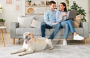 Young couple at home with a tablet and labrador