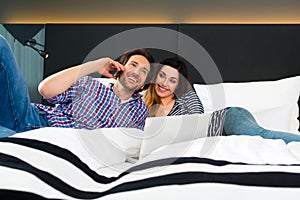 Young couple in Hotel in bed with phone and computer