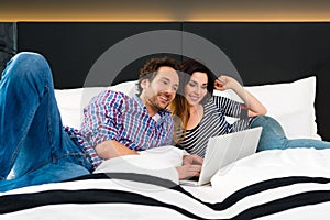 Young couple in Hotel in bed with wifi and computer