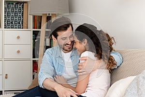 Young couple house buyers cuddle on couch enjoy new home