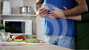 Young couple hugging during dinner preparation in kitchen, care and support