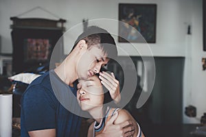Young couple hugging each other tightly, Man comforting his sad mourning girlfriend embracing her in the room.