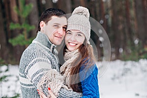 Young couple hugging and kissing in the forest in winter.