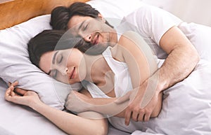Young couple hugging, sleeping together in family bed