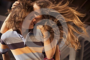 Young couple hugging in the summer daylight on a bridge construction in the city outdoors. copy space