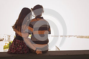 Young couple hugging in the summer daylight on a bridge construction in the city outdoors. copy space