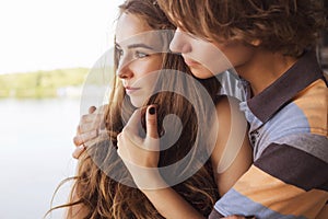 Young couple hugging in the summer daylight on a bridge construction in the city outdoors. copy space