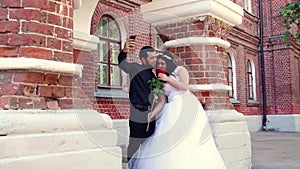 A young couple hugs and is photographed on a smartphone.