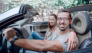 Young couple inside a convertible car for a day trip.