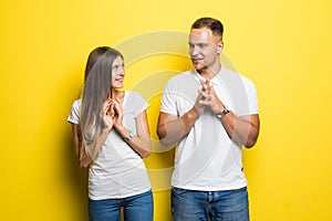 Young couple with insidious and grinning faces smile and something conceived dishonest isolated on yellow background. The concept