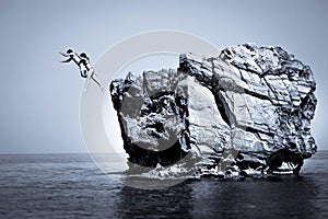 Young couple jumping in sea from rock Black White