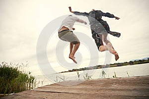 Young couple jumping on the shore of the lake