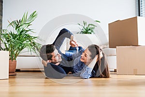 A young couple with a key and cardboard boxes moving in a new home.