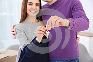 Young couple with key from their new house indoors