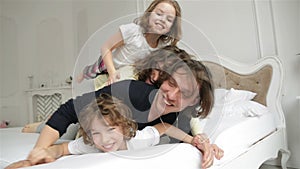 Young Couple with Kids Having Fun Together in the Bedroom. Handsome Husband and Beautiful Wife with Two Children are