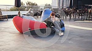 Young couple kisses outdoors. Young hipster couple in love sitting in multi-colored armchairs on the rooftop of