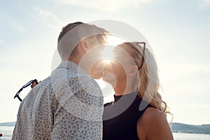 Young Couple Kissing Against Sun At Beach photo