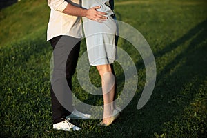 A young couple kissing in a backyard in summer sun light during sunset