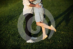 A young couple kissing in a backyard in summer sun light during sunset