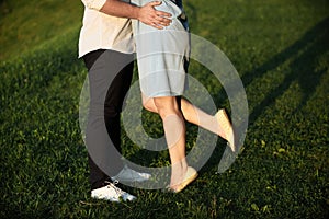 A young couple kissing in a backyard in summer sun light during sunset