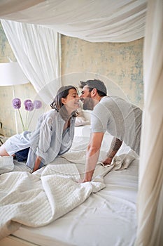 Young couple kissing  in the bedroom while making bed in the morning. bedroom, morning,  togetherness, love concept