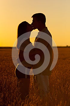 Young couple kissing in the field of wheat