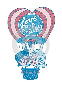 Young couple kissing on a hot baloon with lettering phrase `Love is in the air`.